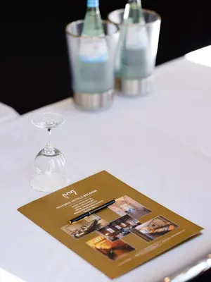 a book on a table with wine glasses and bottles at Ghent River Hotel in Ghent