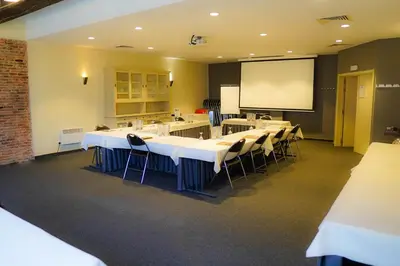 a conference room with tables and chairs and a projection screen at Ghent River Hotel in Ghent