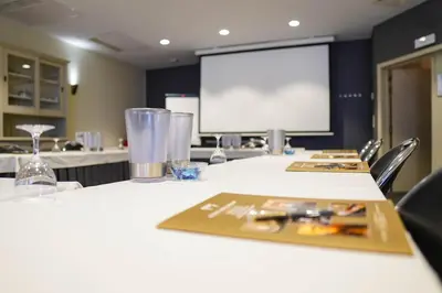 a conference room with a white table with a projection screen at Ghent River Hotel in Ghent