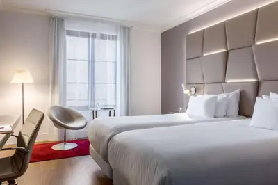 a hotel room with a large bed and a chair at NH Collection Brussels Grand Sablon in Brussels