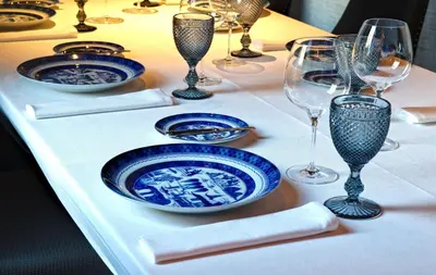a table with blue and white plates and wine glasses at NH Collection Brussels Grand Sablon in Brussels