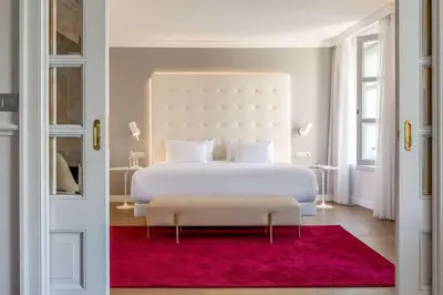 a bedroom with a white bed and a red rug at NH Collection Brussels Grand Sablon in Brussels