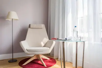 a white chair sitting next to a glass table at NH Collection Brussels Grand Sablon in Brussels