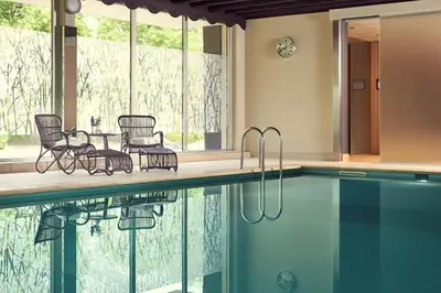 a swimming pool with chairs and a table next to a pool at Van der Valk Hotel Antwerpen in Antwerp