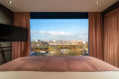 a bedroom with a large window with a view at Van der Valk Hotel Antwerpen in Antwerp