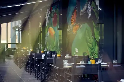 a dining room with tables and chairs and a mural at Van der Valk Hotel Antwerpen in Antwerp