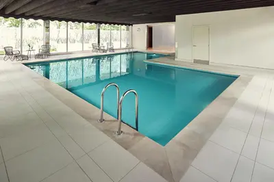 a swimming pool with blue water in a building at Van der Valk Hotel Antwerpen in Antwerp