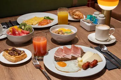 a wooden table with plates of breakfast foods and drinks at Catalonia Brussels in Brussels