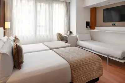 a hotel room with two beds and a tv at Catalonia Brussels in Brussels