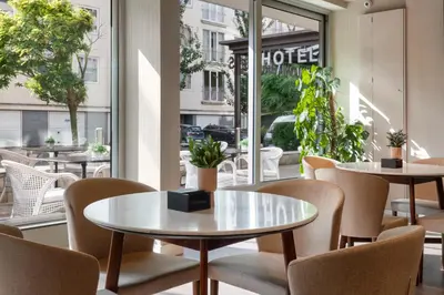 a cafe with tables and chairs in front of a window at Catalonia Brussels in Brussels