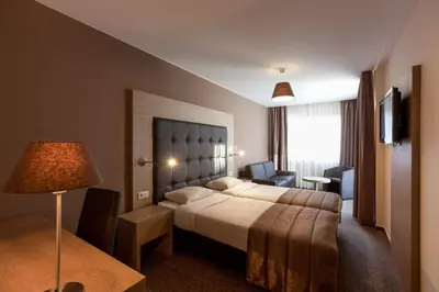 a hotel room with a bed and a desk and a chair at Hotel Villa Royale in Brussels