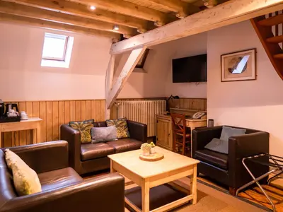 a living room with leather furniture and a tv at Hotel Monasterium PoortAckere Ghent in Ghent