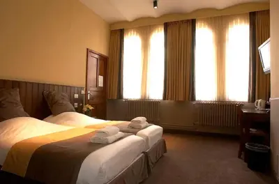 a hotel room with two beds and two windows at Hotel Monasterium PoortAckere Ghent in Ghent