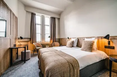 a hotel room with a large bed and a desk at Hotel Monasterium PoortAckere Ghent in Ghent
