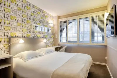 a bedroom with a bed and a wall of books at Hotel Made In Louise in Brussels