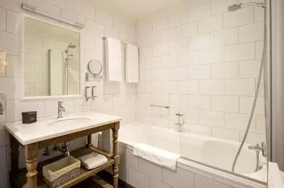 a white bathroom with a sink and a tub at Hotel Made In Louise in Brussels