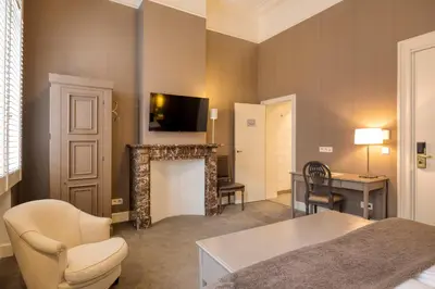 a room with a bed and a fireplace and a television at Hotel Made In Louise in Brussels
