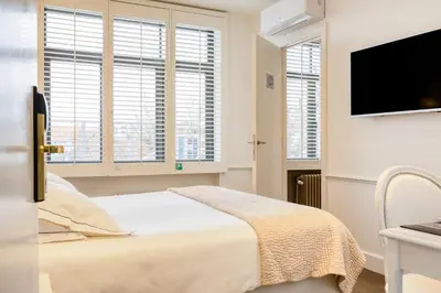a white bedroom with a bed and a flat screen tv at Hotel Made In Louise in Brussels