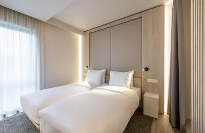 two white beds in a room with a window at Begijnhof Hotel in Leuven