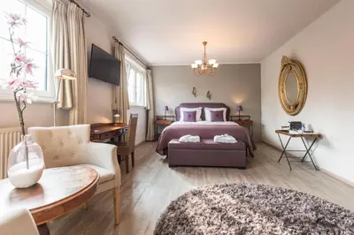 a bedroom with a bed and a chair and a table at Charmehotel Klokkenhof in Brasschaat