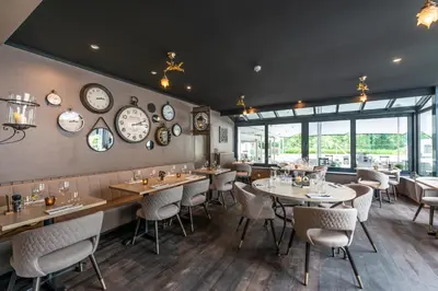 a restaurant with tables and chairs and clocks on the wall at Charmehotel Klokkenhof in Brasschaat