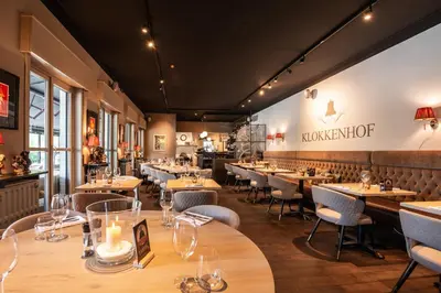 a restaurant with tables and chairs and a sign on the wall at Charmehotel Klokkenhof in Brasschaat