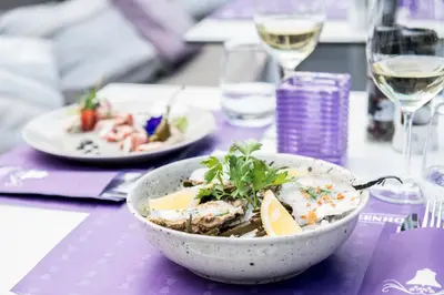 a bowl of food on a table with wine glasses at Charmehotel Klokkenhof in Brasschaat