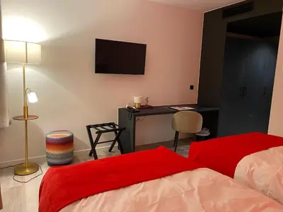 a bedroom with a bed and a desk with a television at Bremberg Hotel in Haasrode