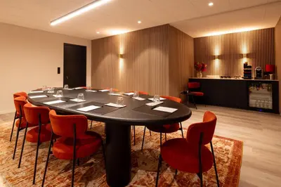 a conference room with a black table and red chairs at Bremberg Hotel in Haasrode