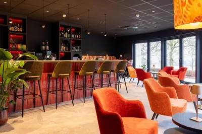 a bar in a restaurant with orange stools at Bremberg Hotel in Haasrode