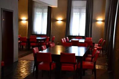 a dining room with tables and red chairs at Hotel De Franse Kroon in Diest