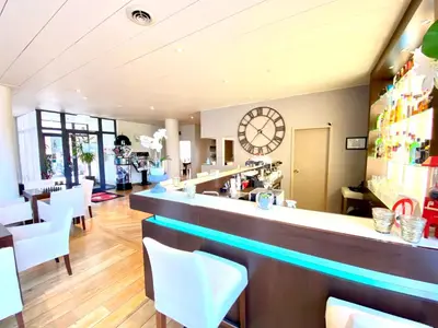a bar with white chairs and a clock on the wall at Hotel De Fierlant in Brussels