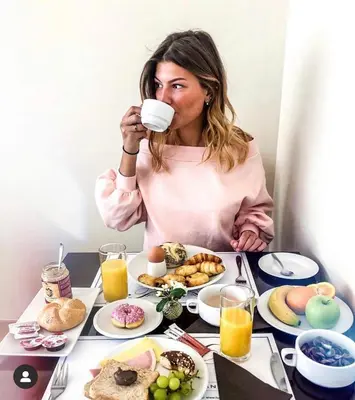 a woman sitting at a table with a cup of coffee at Hotel De Fierlant in Brussels
