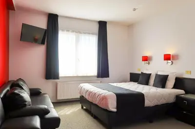 a bedroom with a bed and a couch and a window at Hotel Adoma in Ghent