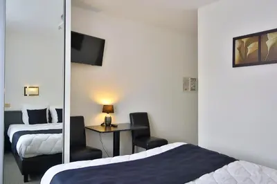 a hotel room with two beds and a mirror at Hotel Adoma in Ghent