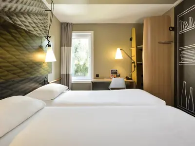 a hotel room with two beds and a window at Ibis Brussels Erasmus in Brussels