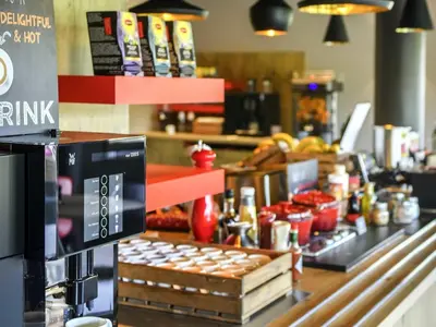 a coffee shop with a counter with food on it at Ibis Brussels Erasmus in Brussels