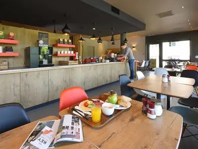 a restaurant with tables and a counter with a man in the kitchen at Ibis Brussels Erasmus in Brussels
