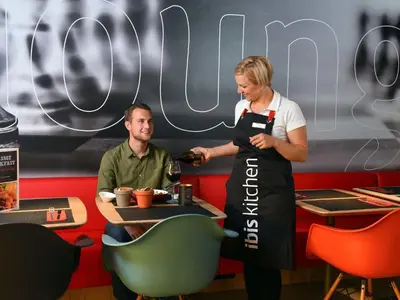 a woman in an apron standing next to a man at Ibis Brussels Erasmus in Brussels