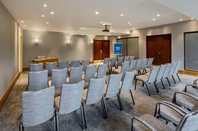 a conference room with rows of chairs and a podium at NH Brussels Airport in Diegem
