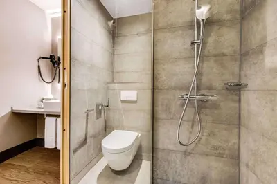 a bathroom with a shower with a toilet and a sink at NH Brussels Airport in Diegem