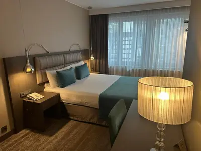 a hotel room with a bed and a table with a lamp at Hotel Agenda Louise in Brussels