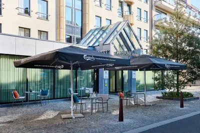 two tables and chairs with umbrellas in front of a building at Keizershof Hotel Aalst in Aalst