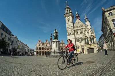 a woman riding a bike in front of a clock tower at Keizershof Hotel Aalst in Aalst