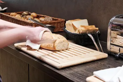 a person cutting a loaf of bread on a cutting board at Keizershof Hotel Aalst in Aalst