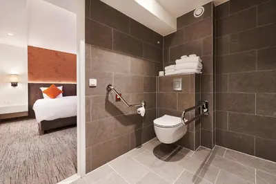 a bathroom with a toilet and a bed in a room at Keizershof Hotel Aalst in Aalst
