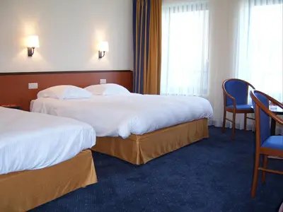 a hotel room with two beds and a chair at Keizershof Hotel Aalst in Aalst