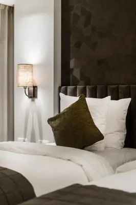 a bedroom with a bed with white pillows and a lamp at Keizershof Hotel Aalst in Aalst