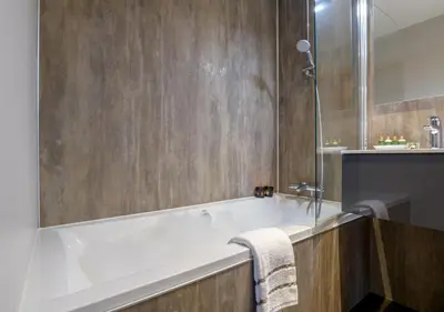a bathroom with a bath tub and a sink at Axis Hotel in Kortenberg
