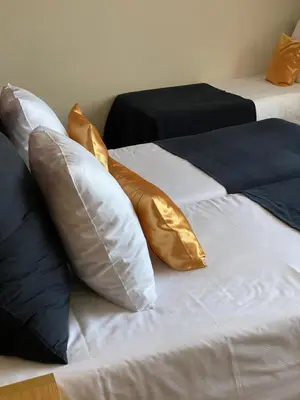 two beds with gold pillows sitting next to each other at Axis Hotel in Kortenberg